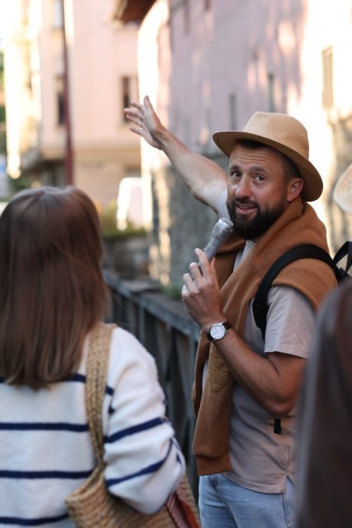 Guide with microphone and tourists on city street during excursion