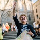 Happy male tourist with modern cellphone technology and paper map for tracking navigation GPS waving and smiling in historic center, cheerful Caucaisan man gesturing hand during solo vacations